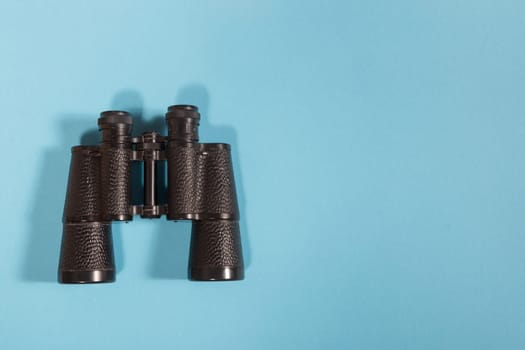 Black metalic binoculars on a blue background