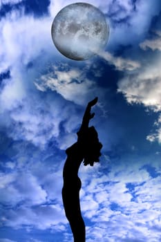 attractive silhouetted nude woman holding her hands up to the sky giving gratitude to the heavens in a yoga pose with a cloudy background
