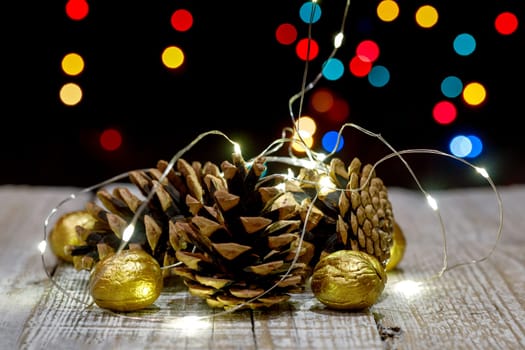Composition of cones and painted walnuts with a garland of lpmpots and bokeh in the background