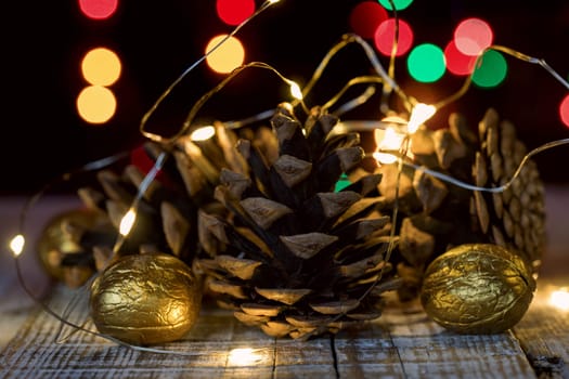 Composition of cones and painted walnuts with a garland of lpmpots and bokeh in the background