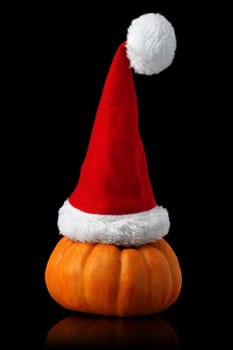 Single orange pumpkin with Christmas Santa hat isolated on black