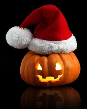 Single orange pumpkin Jack-o-lantern with Christmas Santa hat isolated on black