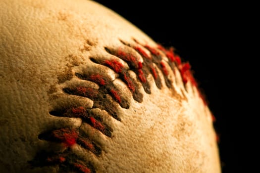 Close up of old worn baseball showing dirty red stitches.