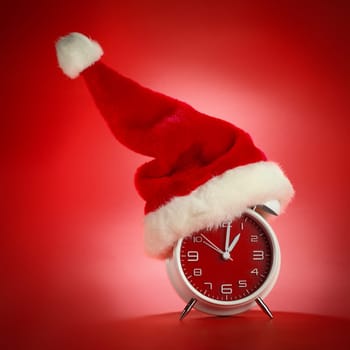 Red clock with Christmas Santa hat. Time for Christmas shopping concept.