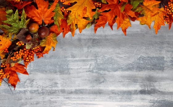 Red, yellow, green, and gold autumn leaves on white washed wooden background
