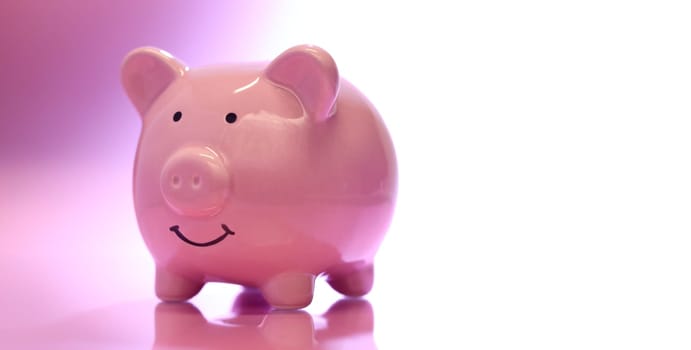 Smiling Piggybank on pink background. Saving money concept.