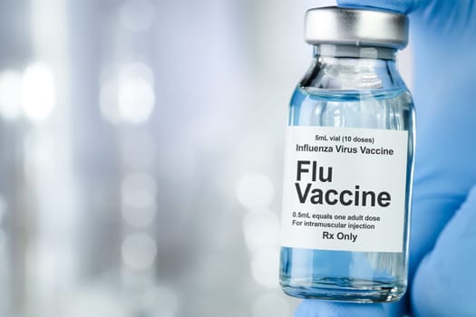 Healthcare concept with a hand in blue medical gloves holding Flu, Influenza, vaccine vial
