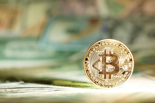 Shiny bright golden bitcoin, balanced on piles of money. Wealth, digital, virtual, currency, and cryptocurrency concept.