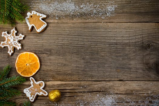 Christmas background from wooden old boards with a place for copy space, cookies in the shape of angels and snowflakes, an orange slice, a golden nut and blue fir