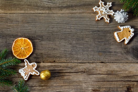 Christmas background from wooden old boards with a place for copy space, cookies in the shape of angels and snowflakes, an orange slice, a golden nut and blue fir