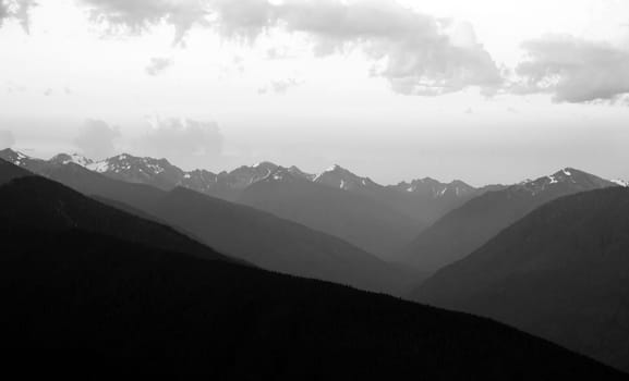 The Olympic Mountains stand against a dramatic sky at sunrise
