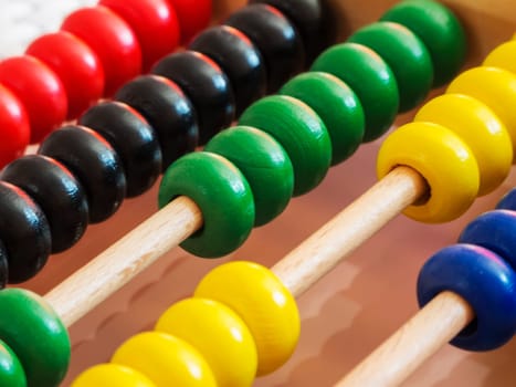 Close-up of a wooden abacus with colorful quills in an oblique view.