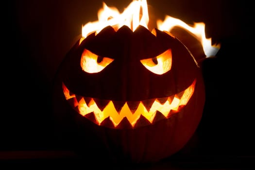 Big helloween autumn symbol with mad face, glowing eyes, mouth and teeth. Scary hot nightmare horror with evil smile at october 31st.