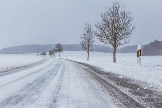 The street track is slick and frozen. High dangerous risk of an accident through the blizzard snowstorm and severe weather at christmas time season.