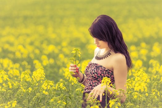 Attractive young beauty girl enjoying the warm sunny sun in nature rapeseed field takes time feeling sustainability and contemplation.