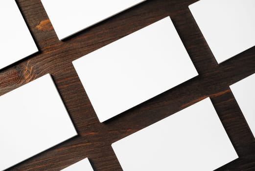 Photo of blank white business cards on wood table background. Template for branding identity.