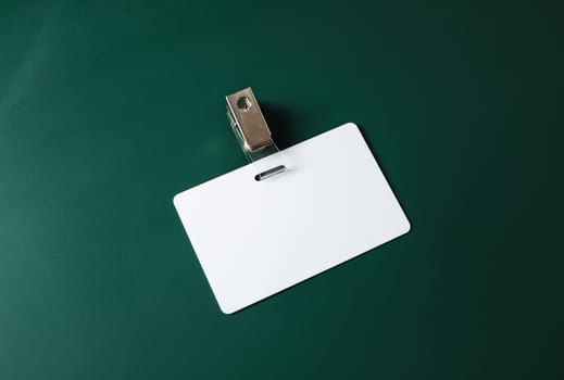 Blank ID card. White plastic badge on green blackboard background. Copy space for text. Responsive design template.