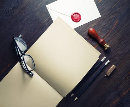 Vintage stationery and open blank kraft paper book or booklet on wooden background. Copy space for text. Flat lay.