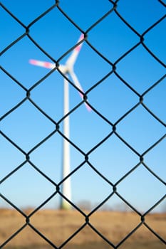 Wind turbine behind a fence in an industrial area in Magdeburg