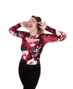 A beautiful young woman wearing a headset and signing along with.the music, with both hands on her head, isolated for white background.