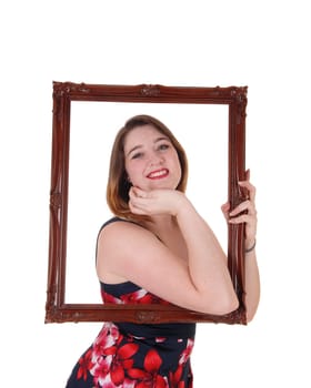 A lovely smiling young woman holding up a picture frame and looking.trough, smiling, isolated for white background.