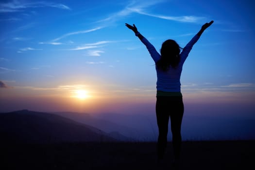Silhouette of young woman against sunset with blue sky