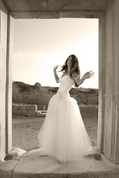 Beautiful bride in the white dress at greece ancient door. Black and white, sepia