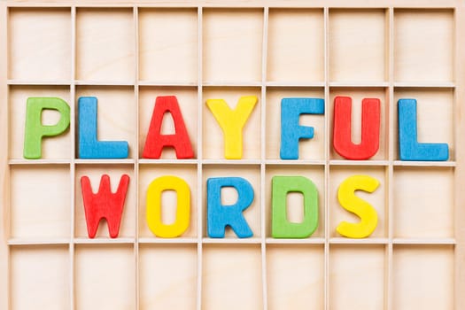 Playful words text from colorful wooden letters are on wooden background, education, learning english or mother language concept.