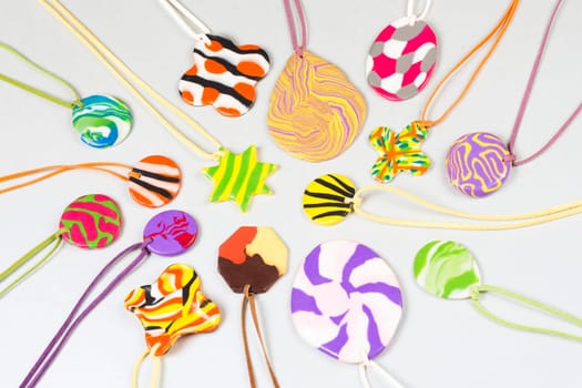 Lovely colorful handmade jewelry from plasticine on light gray background, crafts and creativity.