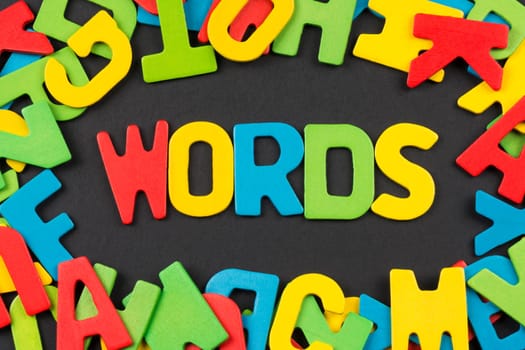 The "WORDS"" text from colorful letters around colorful letters on dark background, english language concept."