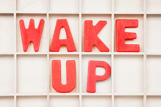 WAKE UP text written by red wooden letters on board, morning or state of mind concept.