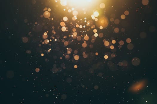 Abstract glittering gold with bokeh and dust effect . Black background .