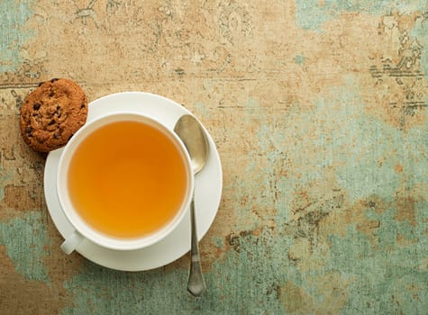Cup of green and herbs tea served with cookie on wooden table