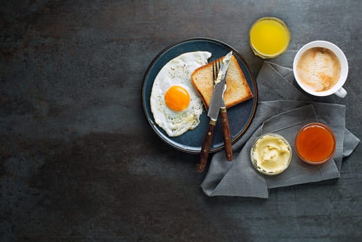 Breakfast served with fried egg, jam, butter, coffee and juice on the table top view. Heathy breakfast food