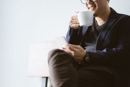 Coffee in businessman hand with with smartphone , selective focusing .