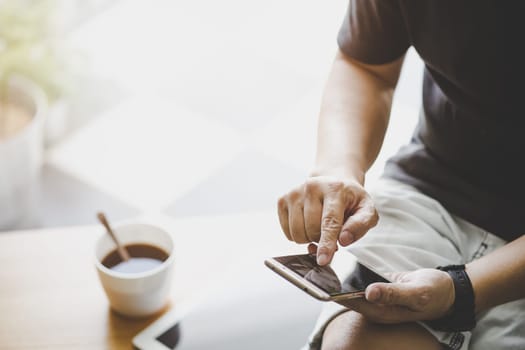 Smartphone in young man hand with digital tablet and coffee .