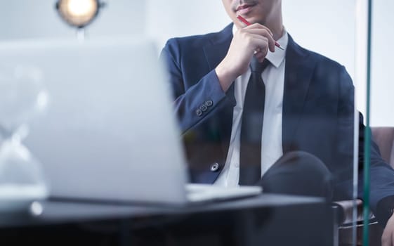 Young asian businessman holding pen and think about the financial plan