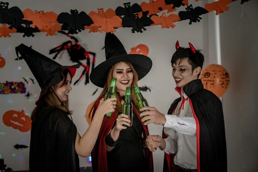 Group of young adult and teenager people celebrating a Halloween party carnival Festival in Halloween costumes drinking alcohol beer - Selective focus at beer bottless