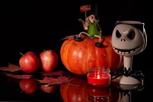 Halloween still life with pumpkin, autumn leaves, candle and witch on a black background. Halloween background