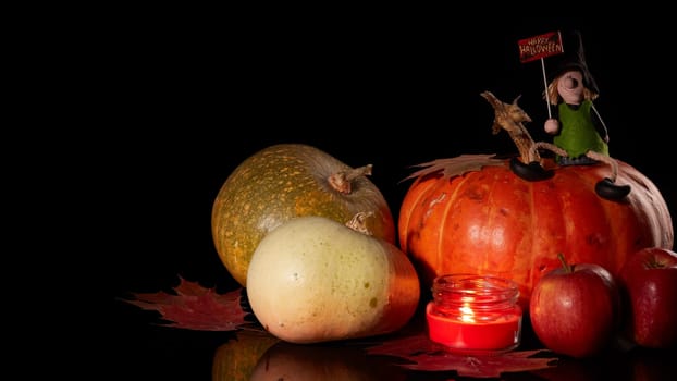 Halloween still life with pumpkin, autumn leaves, candle and witch on a black background. Halloween background