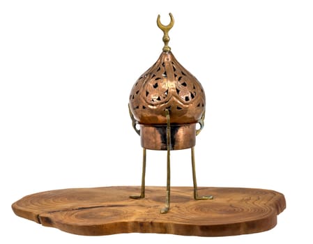 Old oriental incense burner made of copper stands on a wooden disc isolated on white