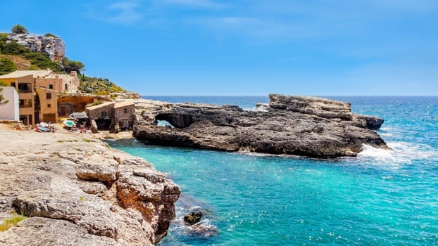 Panorama of beautiful beach and bay with cliffs and turquoise sea water, traditional house village at Cala sAlmunia, Santanyi, Mallorca island, Spain