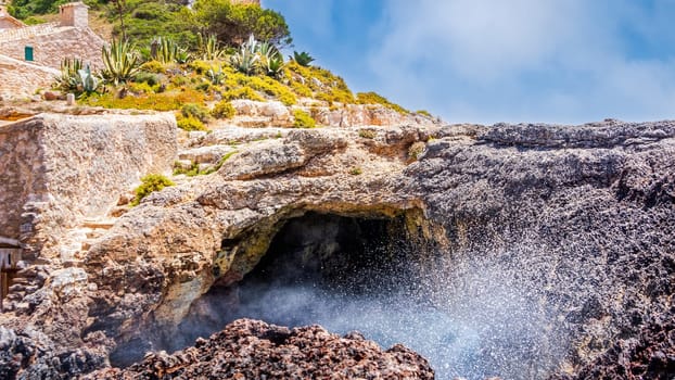 Sea water erupting from under natural cave on the cost of Cala sAlmunia, Santanyi, Mallorca island, Spain