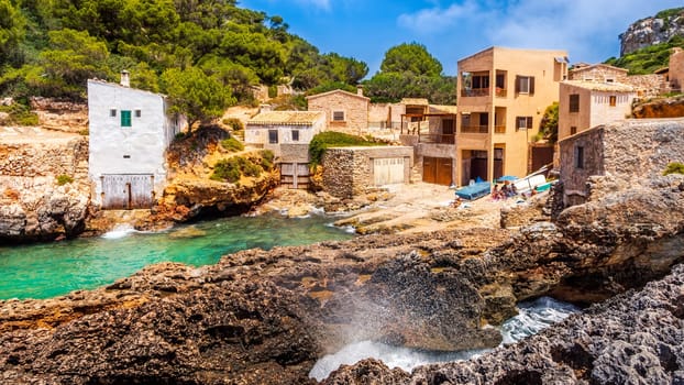 Panorama of beautiful beach and bay with cliffs and turquoise sea water, traditional house village at Cala sAlmunia, Santanyi, Mallorca island, Spain