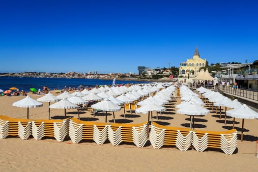 Rows of white umbrellas at the concessioned beach of Tamariz Beach, in Estoril, Portugal