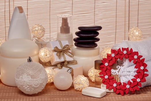 Spa still life with cosmetic creams, towel, black stones, gift boxes and Christmas ornaments standing on bamboo mat. Christmas Healthy lifestyle, body care, Spa treatment and relaxation concept