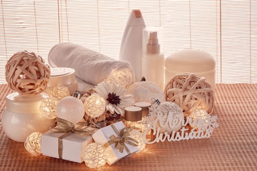 Spa still life with cosmetic creams, towel, gift boxes and Christmas ornaments standing on bamboo mat. Christmas Healthy lifestyle, body care, Spa treatment and relaxation concept