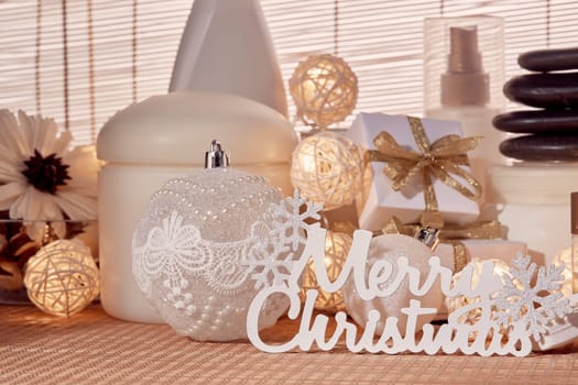 Spa still life with cosmetic creams, towel, black stones, gift boxes and Christmas ornaments standing on bamboo mat. Christmas Healthy lifestyle, body care, Spa treatment and relaxation concept