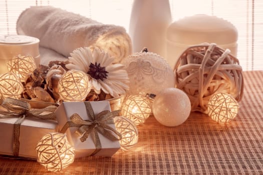 Spa still life with cosmetic creams, towel, gift boxes and Christmas ornaments standing on bamboo mat. New Year and Christmas Healthy lifestyle, body care, Spa treatment and relaxation concept
