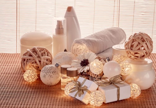 Spa still life with cosmetic creams, towel, gift boxes and Christmas ornaments standing on bamboo mat. New Year and Christmas Healthy lifestyle, body care, Spa treatment and relaxation concept